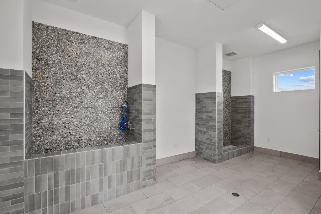 a large bathroom with two showers and a tile floor