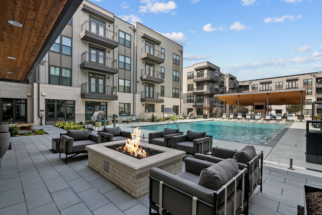 an outdoor patio with chairs and a fire pit and a pool