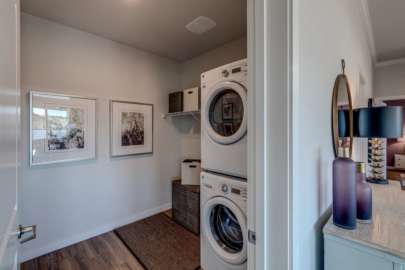 Lux Apartments Bellevue WA in-unit laundry room with front loading washer and dryer and additional storage space.