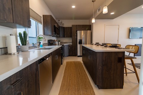 A modern kitchen with dark wood cabinets and stainless steel appliances.