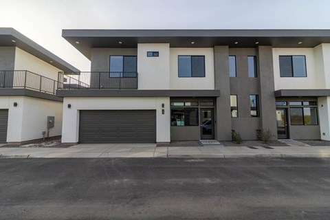 A modern two-story building with a garage door and balcony.
