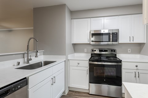 A modern kitchen with a stainless steel oven and white cabinets.