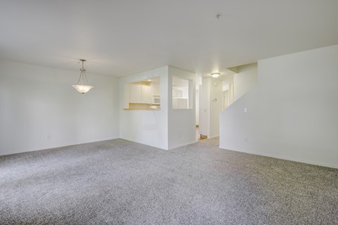 A spacious room with a carpeted floor and a chandelier hanging from the ceiling.