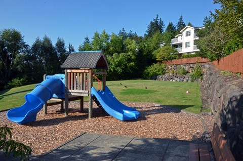 A playground with a blue slide and a wooden structure.