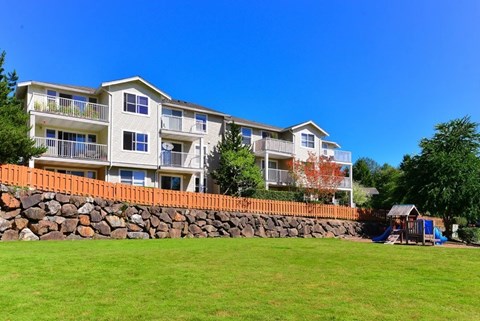 A large apartment building with a stone wall in front.