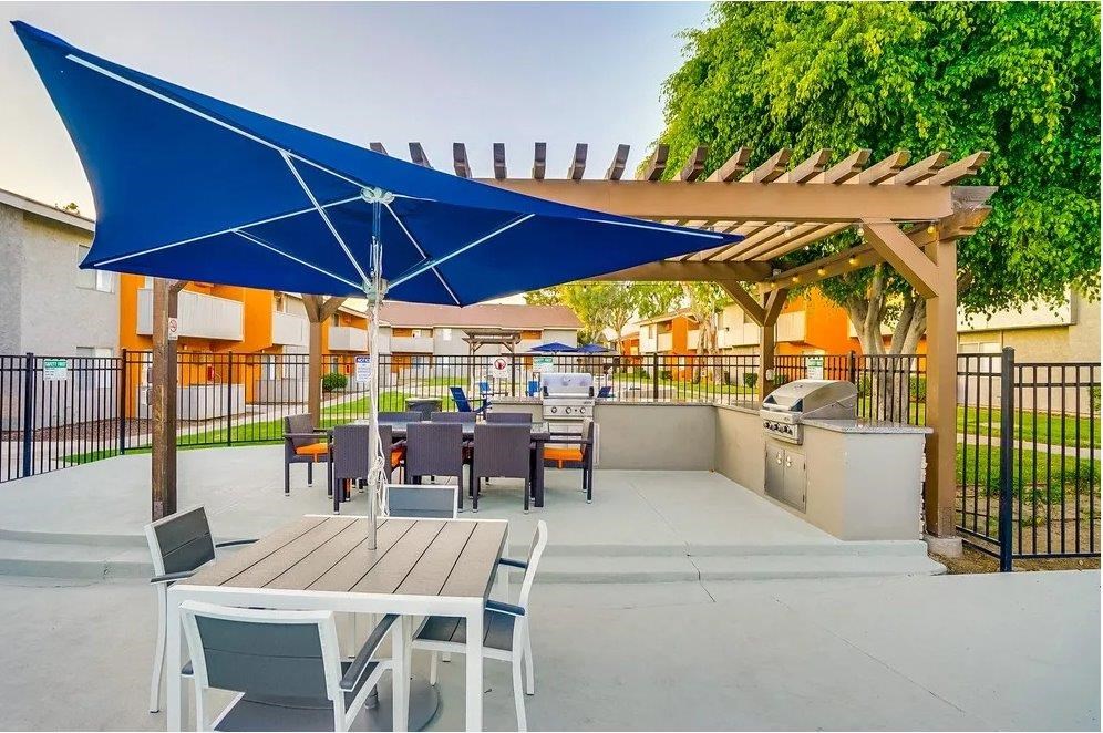 A patio with a table and chairs under a blue umbrella.