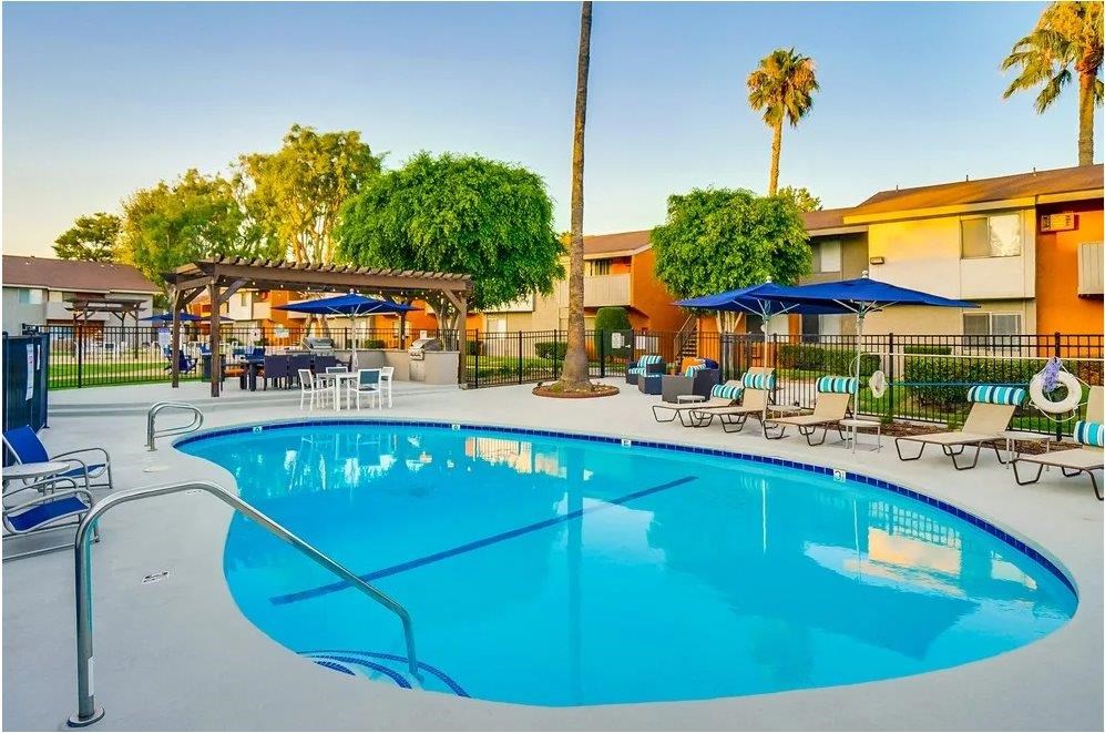 A large swimming pool with a metal railing and a few chairs around it.
