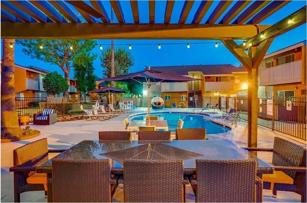 A poolside area with a table and chairs under a canopy.