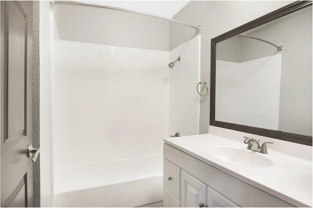 A white bathroom with a sink and mirror.