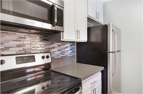 A modern kitchen with a stove, microwave, and refrigerator.