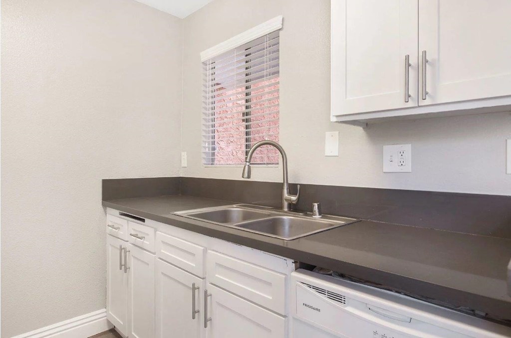 A kitchen with white cabinets and a stainless steel sink.
