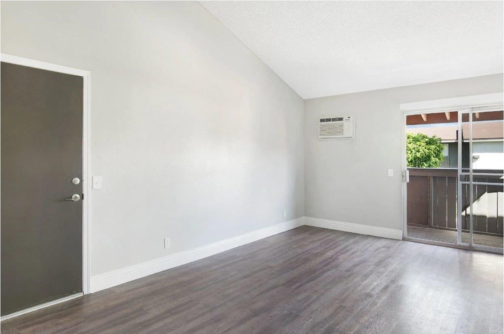 A room with a wooden floor and a door on the left.