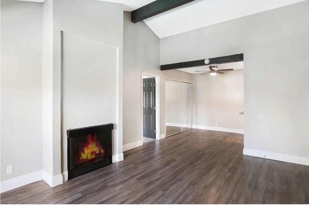 A room with a fireplace and wood flooring.