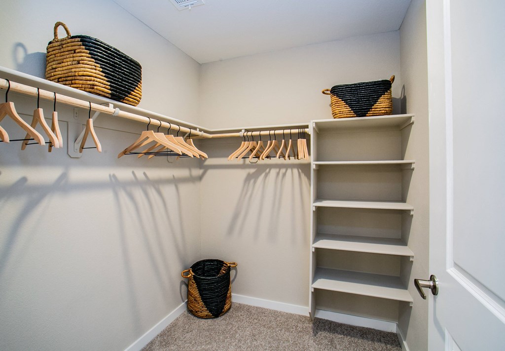the walk in closet with shelves and baskets in a new home