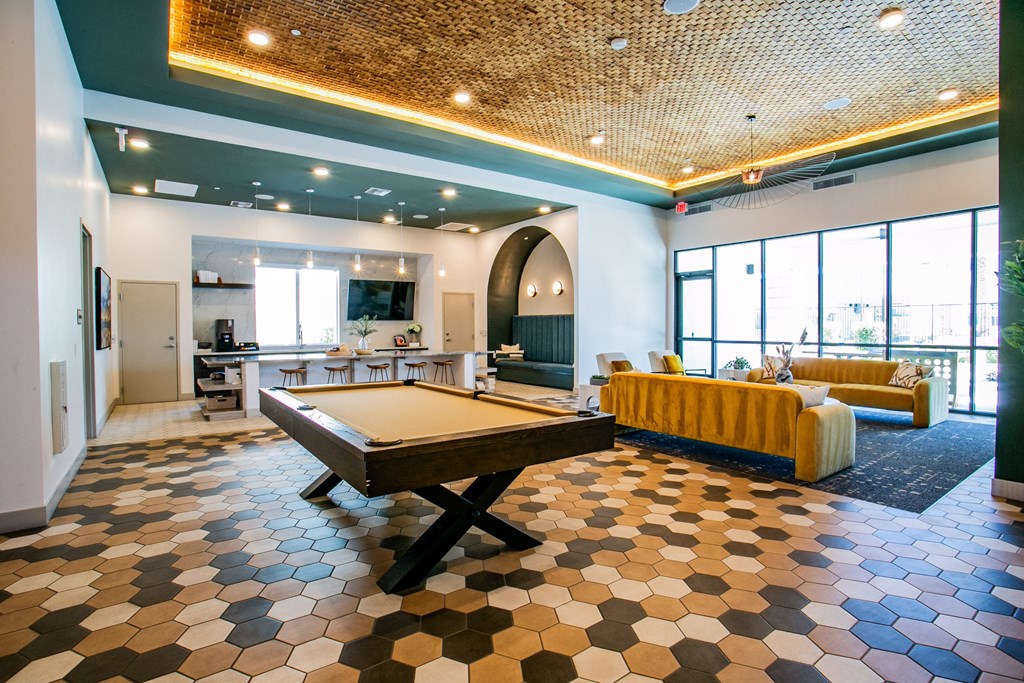 a spacious game room with a pool table and a bar