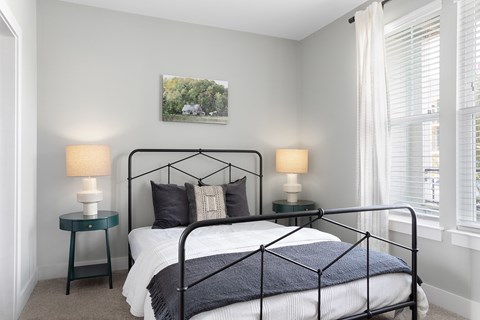 A bedroom with a black metal bed frame and a white bedspread.