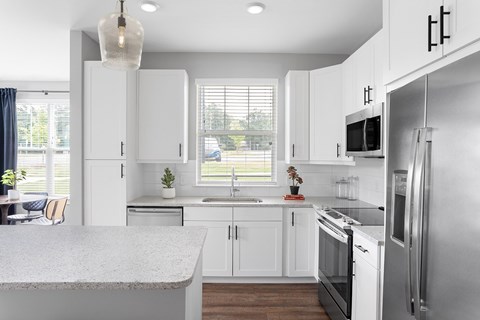 A modern kitchen with white cabinets and stainless steel appliances.