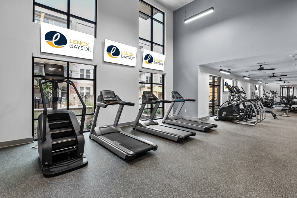a gym with treadmills and other exercise equipment in a building with large windows