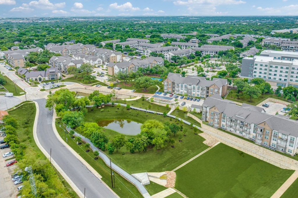 A bird's eye view of a residential area with houses and a pond.