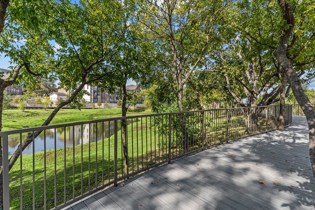 A wooden walkway with a metal railing runs through a grassy area.