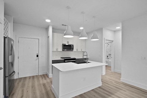 a white kitchen with a large island and a refrigerator