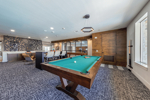 A pool table is in the middle of a room with a patterned carpet.