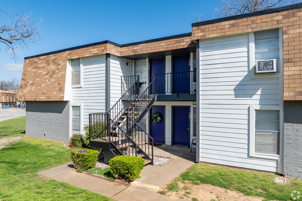the front of an apartment building with stairs and a blue door