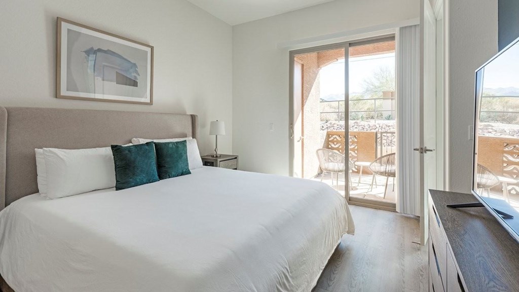 A bedroom with a large bed and a painting on the wall.