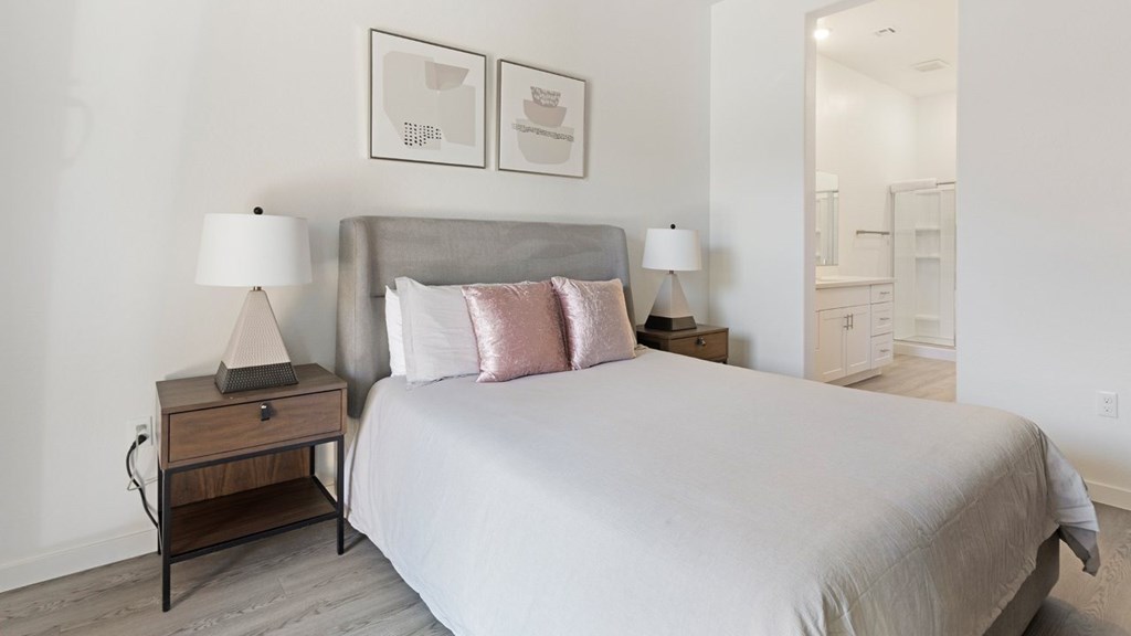 A bedroom with a large bed and two nightstands with lamps.