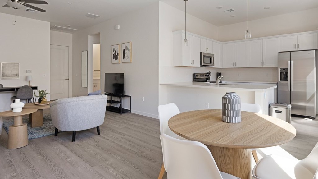 A modern kitchen and living room with white furniture and a grey sofa.