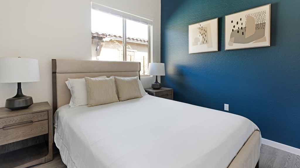 A bedroom with a large bed and two lamps.