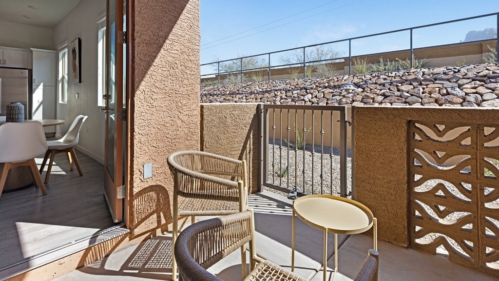 A patio with a table and chairs overlooking a rocky landscape.