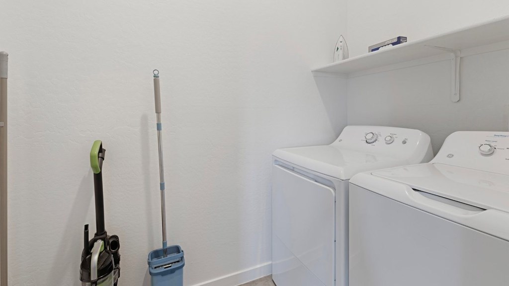 A white wall with a mop and a dustpan on it.