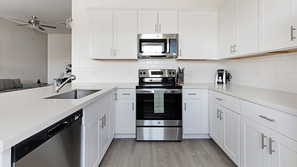 A modern kitchen with white cabinets and stainless steel appliances.