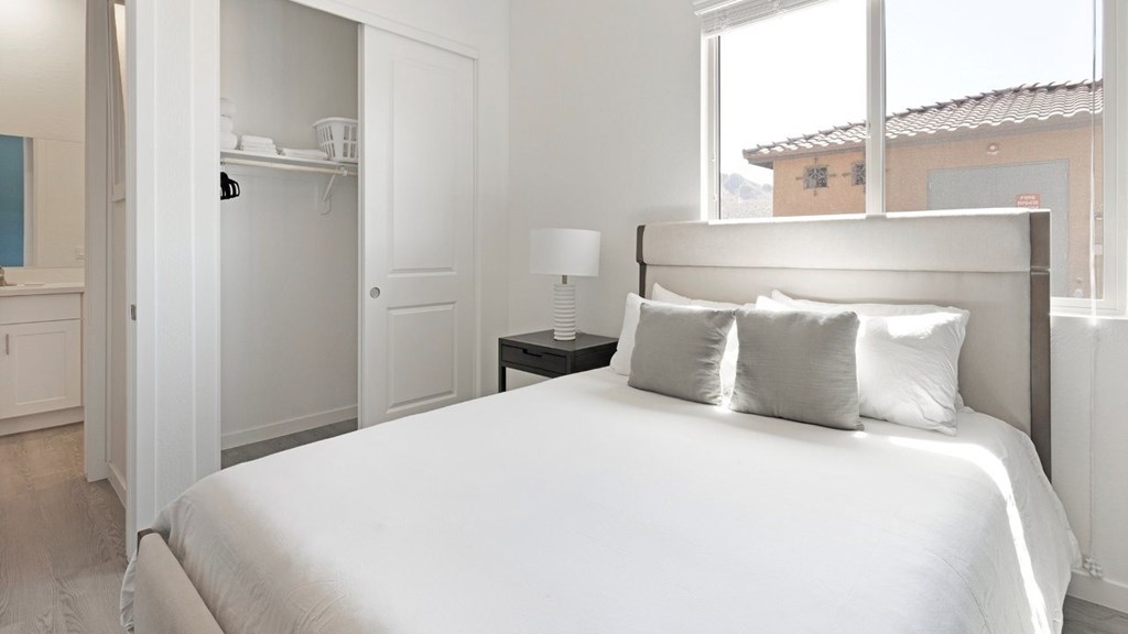 A white bed with a white headboard and two white pillows.