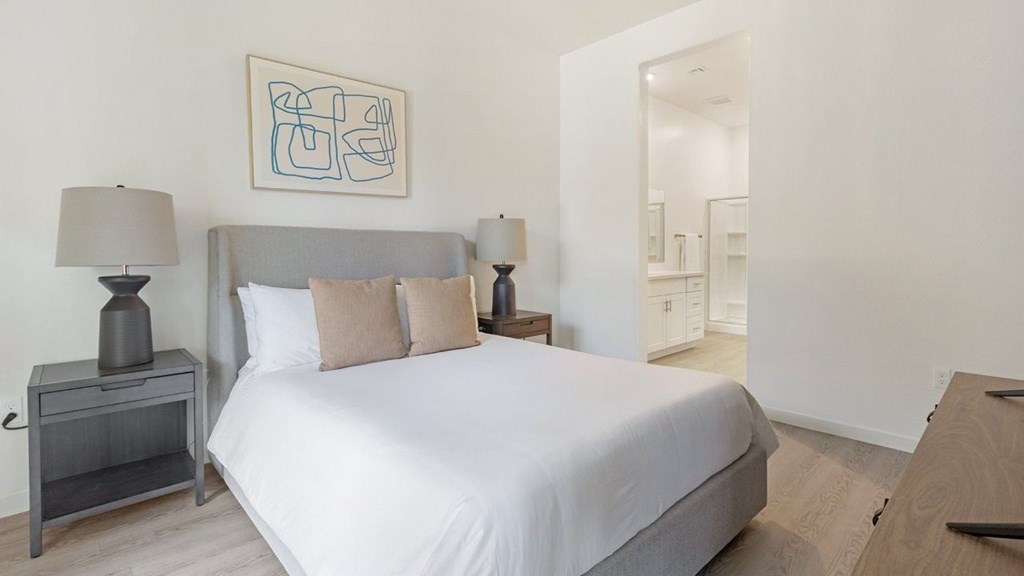 A bedroom with a bed, nightstand, and lamp.