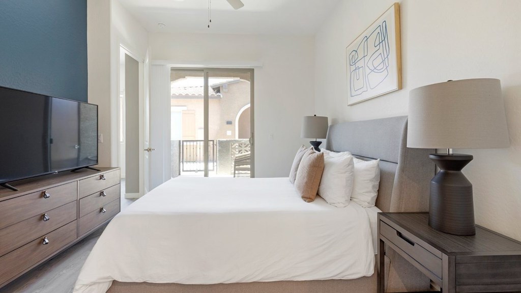 A bedroom with a large bed, a television, and a painting on the wall.