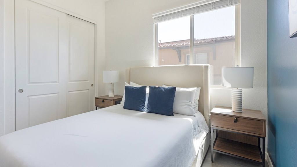 A bedroom with a large bed, two lamps, and a nightstand.