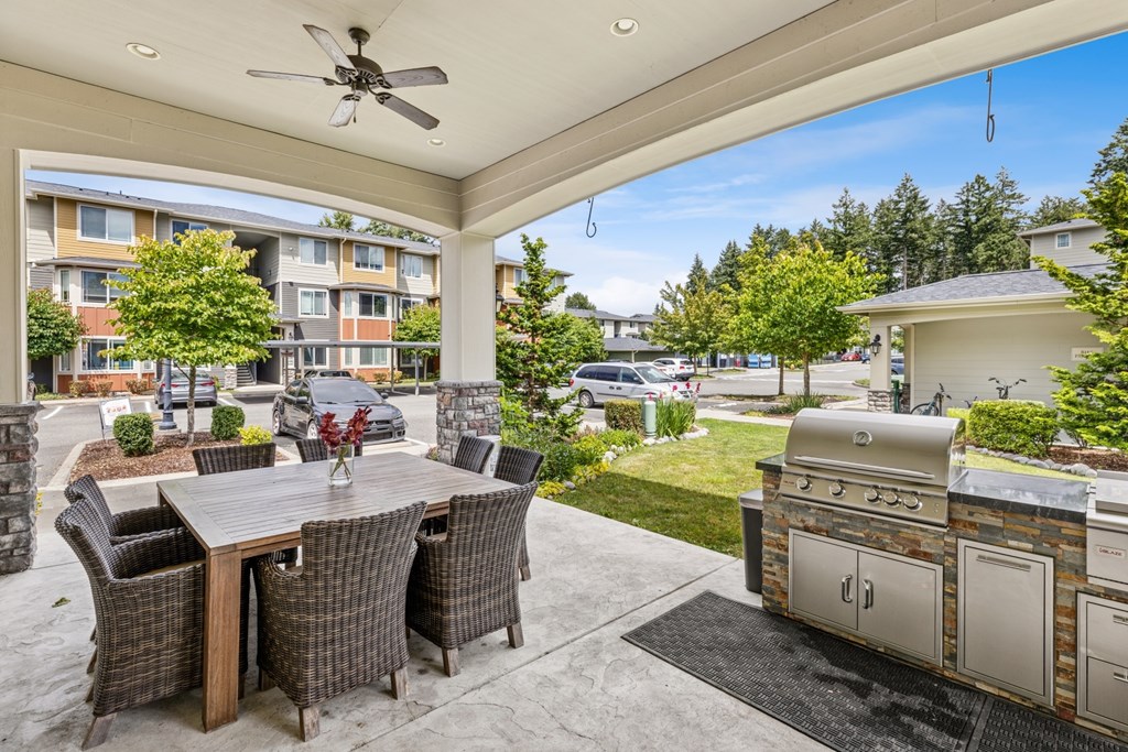 A patio with a table and chairs and a grill.