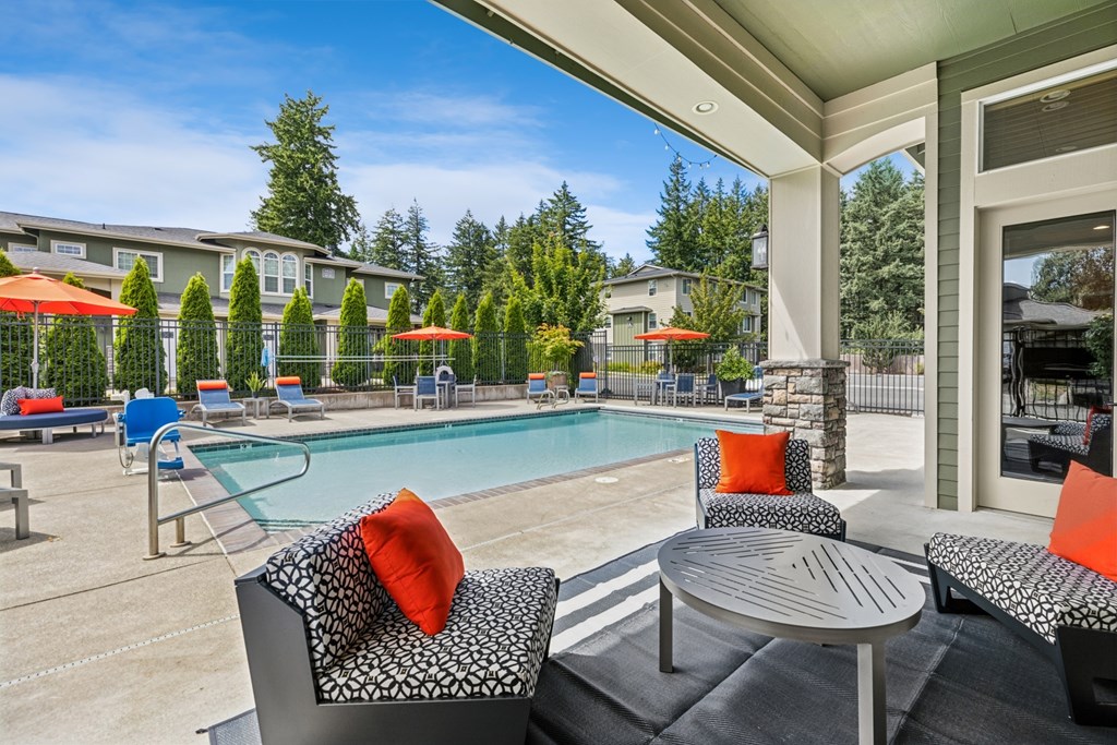 A patio with a table and chairs overlooking a pool.