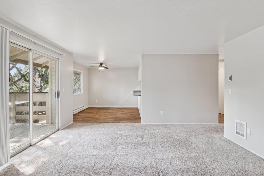 A spacious living room with a carpeted floor and a ceiling fan.
