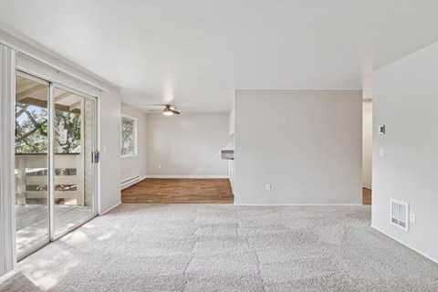 A spacious living room with a carpeted floor and a ceiling fan.