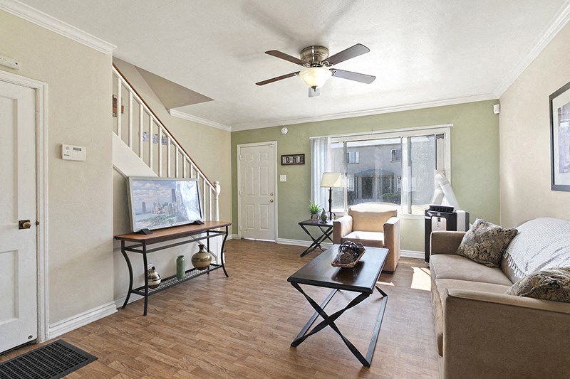 a living room with a staircase in the background and a couch and chair in the foreground