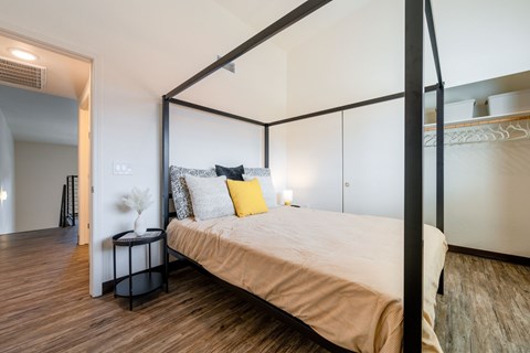 A bedroom with a four-poster bed and a nightstand with a vase of flowers on it.