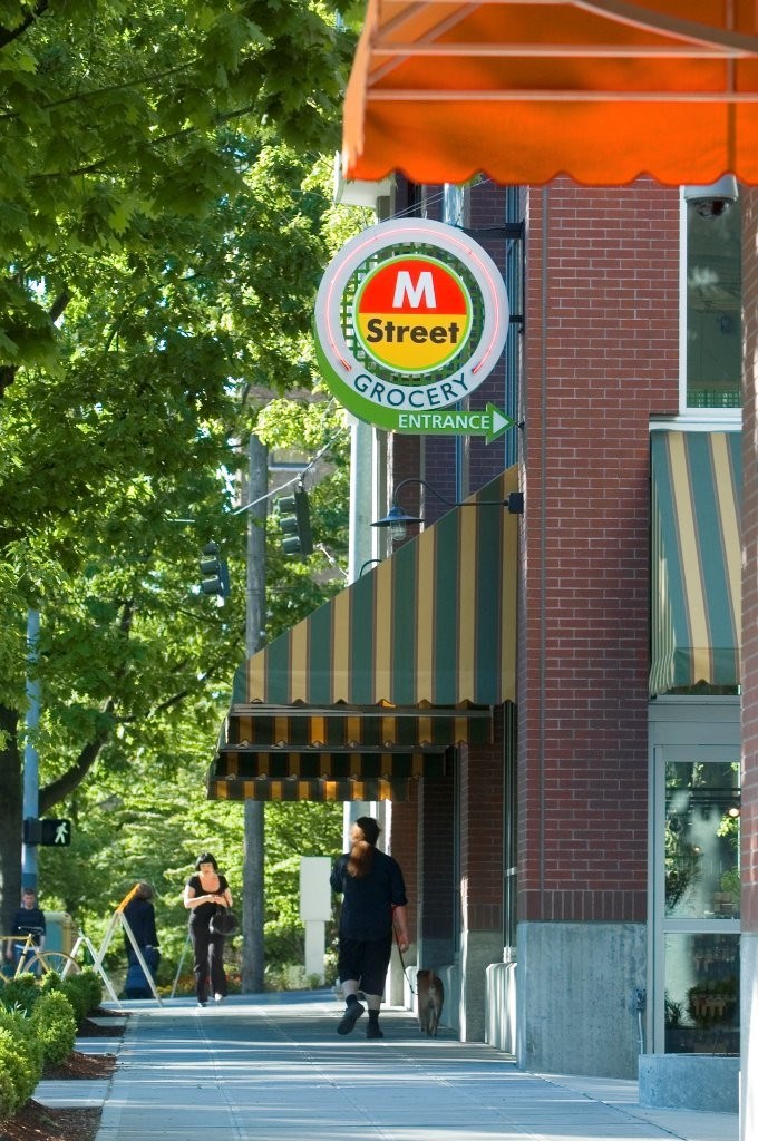 A street sign for M Street Grocery entrance is hanging from a pole.