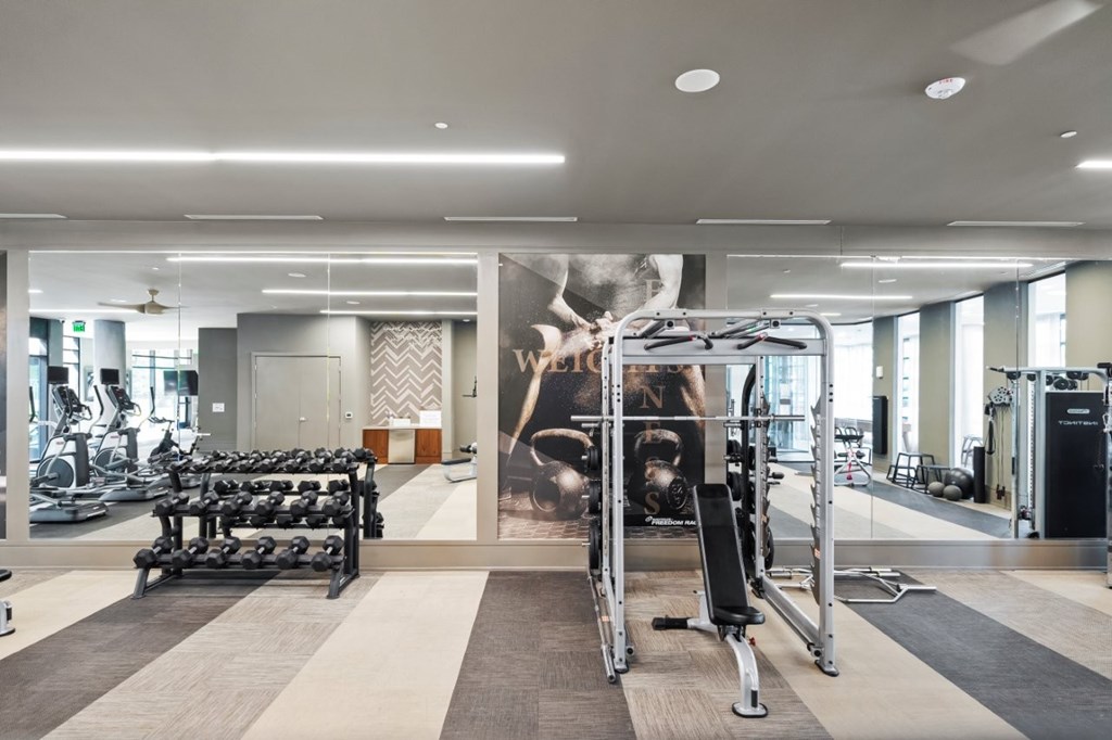 A gym with a variety of equipment including weights and cardio machines.