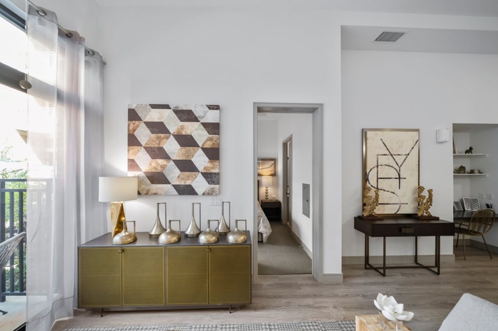 A modern living room with a gold cabinet and a large abstract painting on the wall.