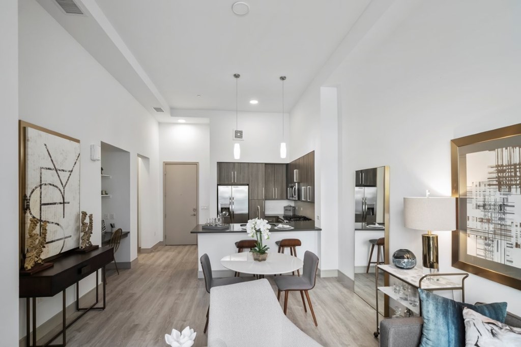 A modern living room with a dining area and a kitchen in the background.