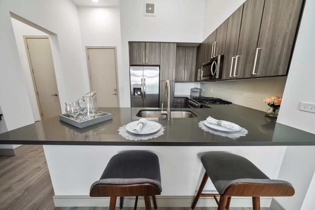 A kitchen with a black countertop and two chairs.