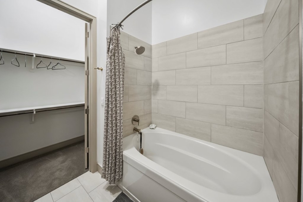 A white bathtub with a shower head and a curtain.